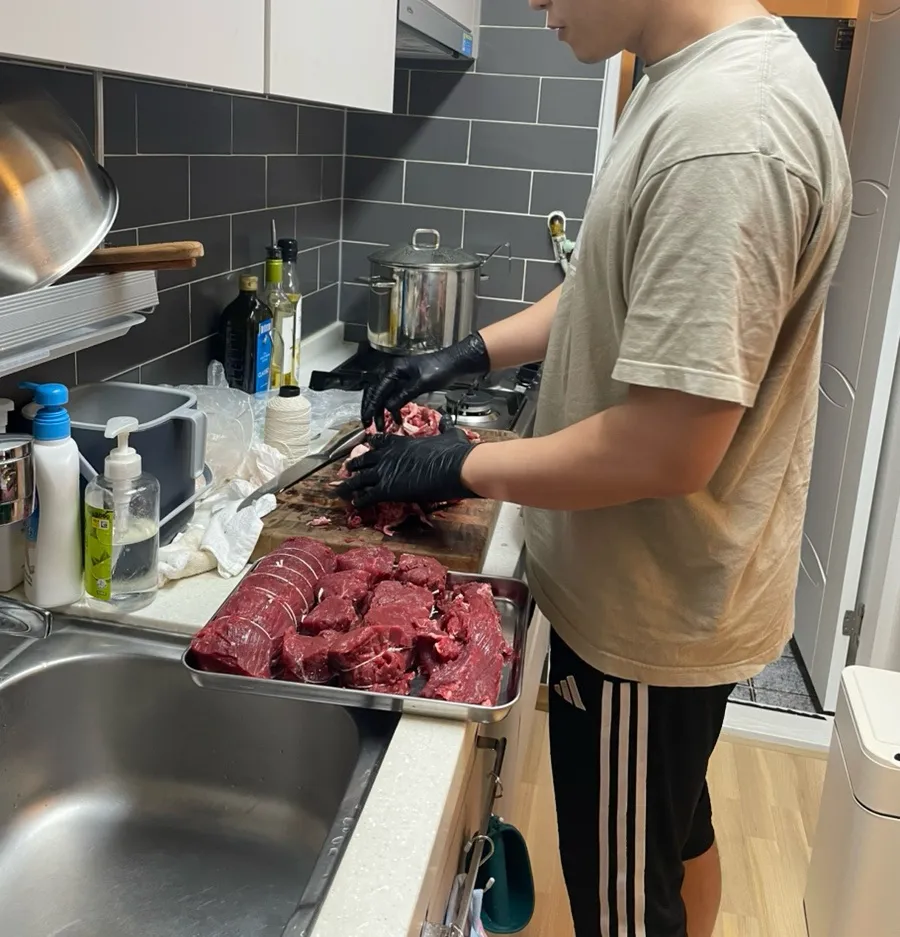 Yeoseong preparing meat in a cramped kitchen the night before the party